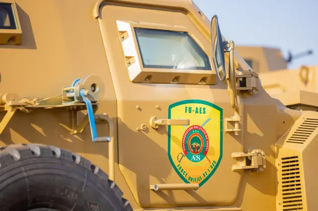 A military vehicle with a yellow color scheme displaying a 'FU-AES' sign.