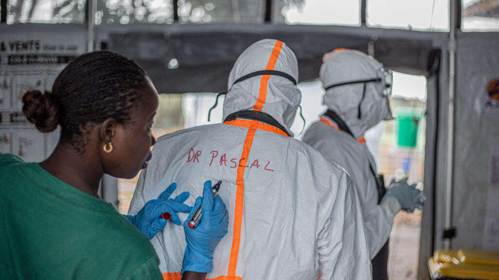 A health worker writes a doctor's name on the back of their personal protective equipment before entering the Ebola treatment center in Rwampara to care for patients infected with the Ebola virus disease, in Bunia (Ituri), eastern Democratic Republic of Congo, on July 13, 2026.
